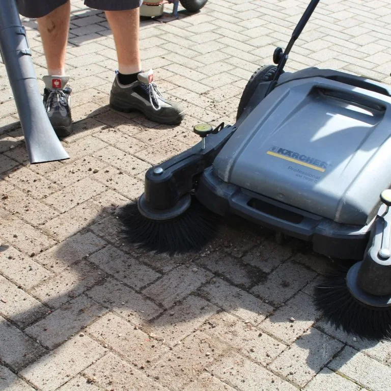 Kehrmaschine bei der Reinigung eines gepflasterten Hofes